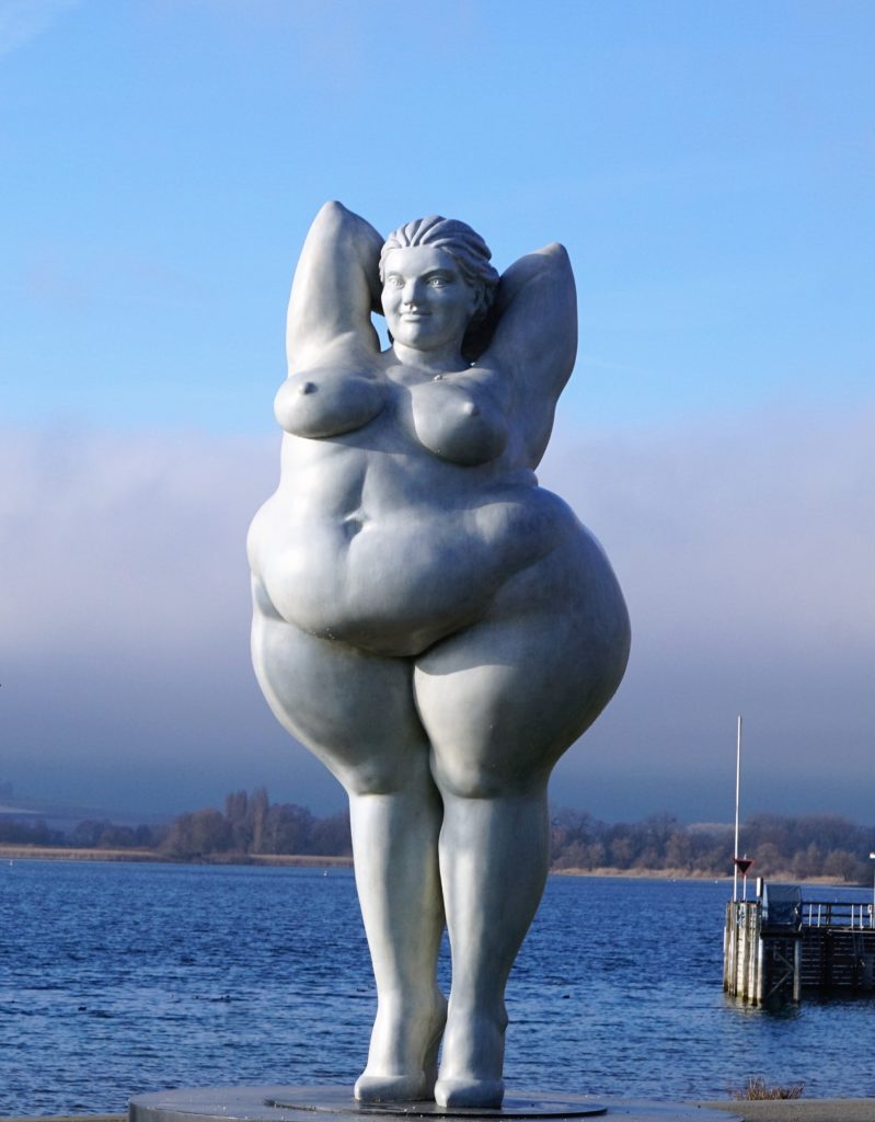 Escultura hecha en piedra de una mujer robusta.